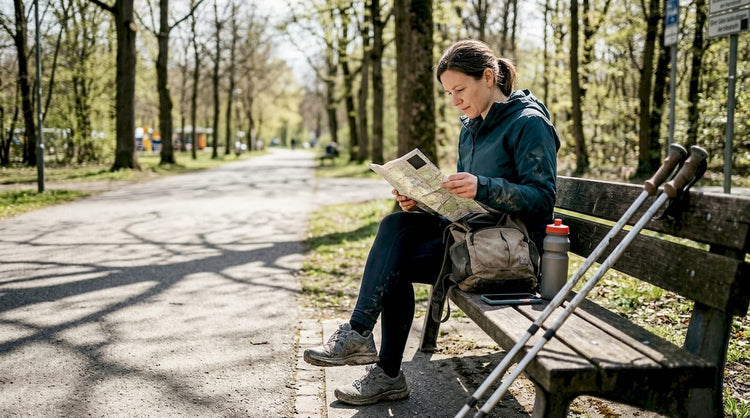 Eine Frau sitzt auf einer Parkbank und macht ihre Ausrüstung für die nächste Geocaching-Tour startklar.