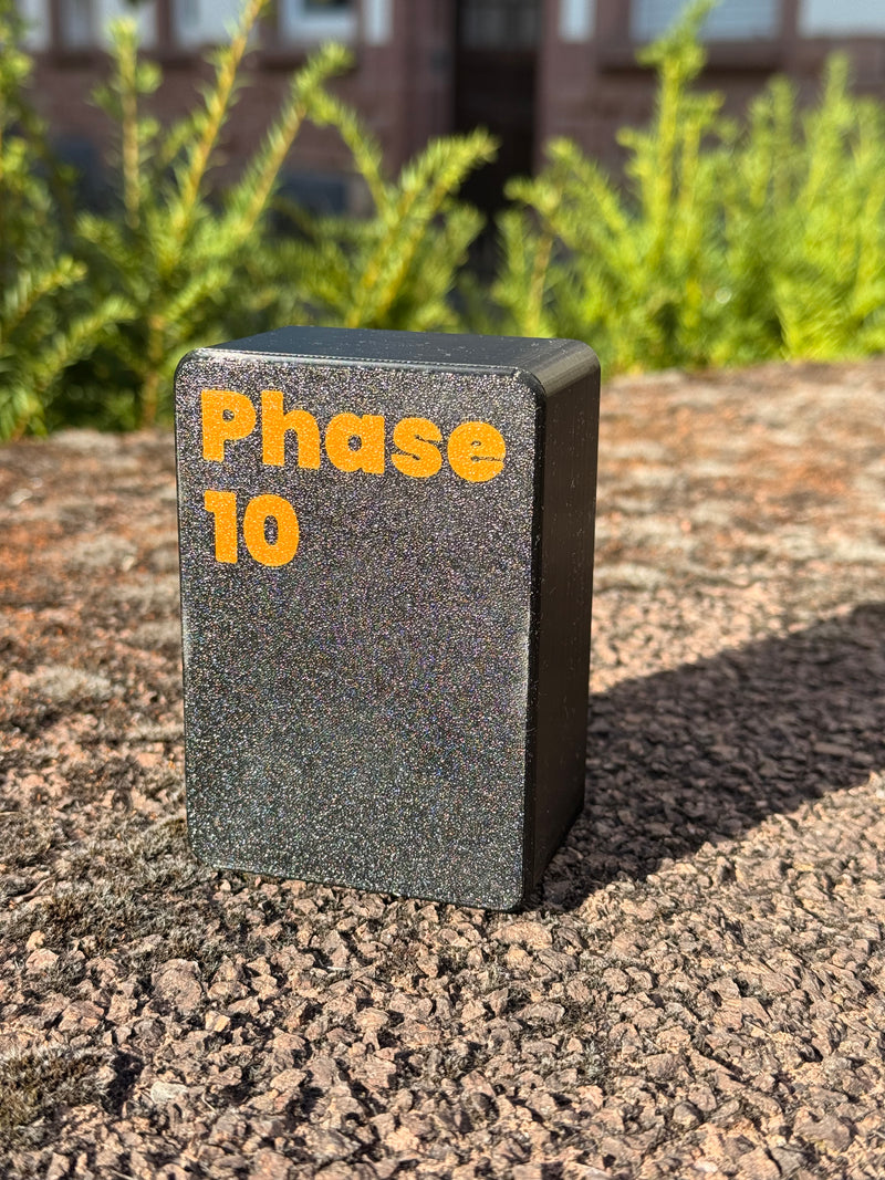 Laden Sie das Bild in Galerie -Viewer, CacheWerk GameBox für Phase 10 – geschlossene schwarze Kartenbox mit orangefarbener Beschriftung
